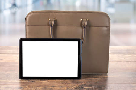 Mock Up Digital Tablet pc With blank screen. Workspace with Bag, business briefcase, mockup blank digital tablet on wooden office tableの写真素材