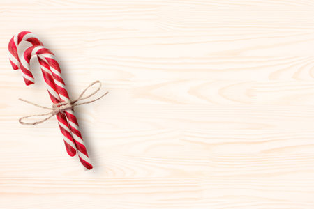 Christmas card with candy canes. Red and white candy canes on light wood table board with copy space. top view. copy spaceの写真素材