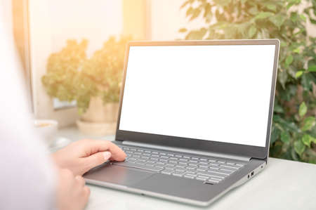 hand typing mockup laptop computer showing blank white screen on table office place. blank screen...