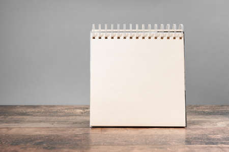 mockup notepad. Blank spiral bound notepad mockup with on light gray background and wooden table....