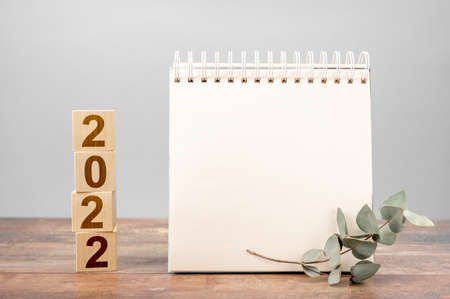 2022 time for a new start. Plan words and 2022 cubes wooden table background. New Year. plans for 2022, space for your text on notepad, mockup calendarの写真素材