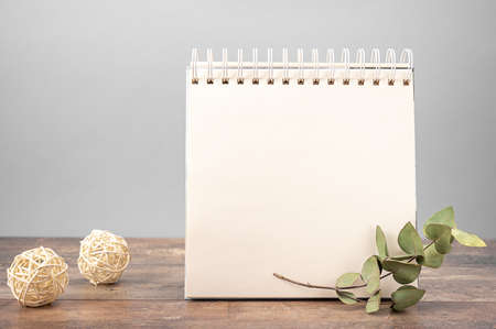 mockup of notebook with white blank sheet of paper stands on wooden table on gray background decorated with dry flowersの写真素材