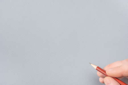 One man's hand with the pencil on gray paper background. copy space. Close Up Of Human Hand With Pencil. Human Hand Drawing With Pencil On Empty gray Paper Template. Pencil on the paper, close upの写真素材