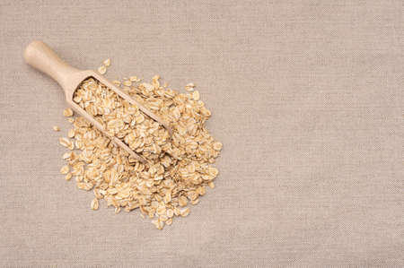 oatmeal cereal. scoop and pile of oatmeal with its plant. Dry rolled oatmeal. wooden scoop with Oat flakes. copy space. top viewの写真素材