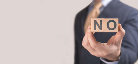 Businessman show wording NO on wooden cubes. Negative answer concept. No risk, refusal to hire...