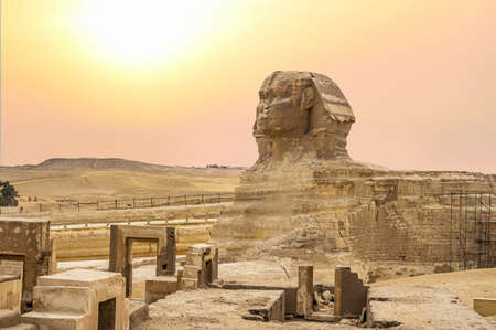 Landscape with Egyptian pyramids, Great Sphinx and silhouettes Ancient symbols and landmarks of Egypt for your travel concept to Africa in golden sunlight. Sphinx head against the yellow skyの写真素材