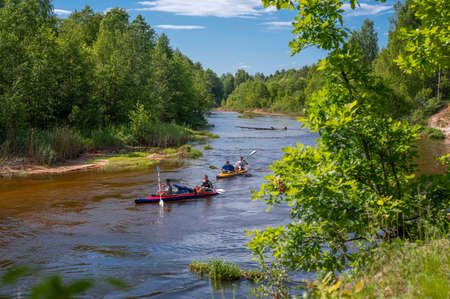 canoeing on forest river. Friends driving with kayak on forest river. active pastime and entertainment in summer. Several people team inflatable canoes rafting in calm waters with nice surroundingのeditorial素材