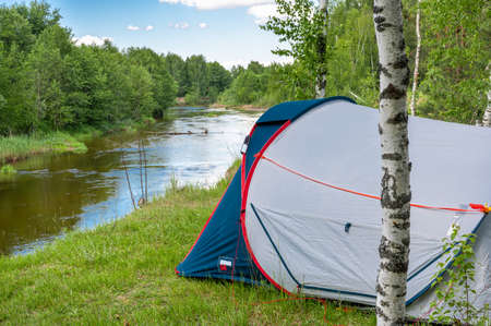 Camping tent in a forest by the river. Tourist tent in forest. tourist background. Nature tourism, Lifestyle and camping holiday conceptの写真素材