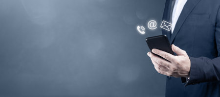 CONTACT US. businessman holding cell phone with with mail, phone, email icon. cutomer support...