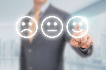 Businessman pressing excellent smiley face rating icon over light blue background, customer service evaluation and feedback rating concept. costumer review concept, man pointing on happy smiling faceの写真素材
