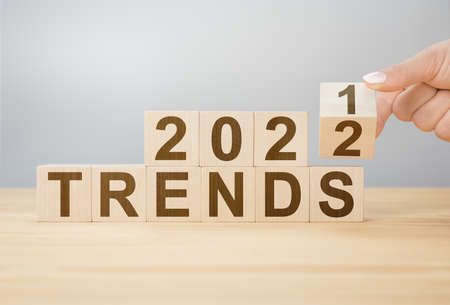 Trends 2022 blocks. 2022 trends new year symbol. woman turns a wooden cube and changes words Trends...