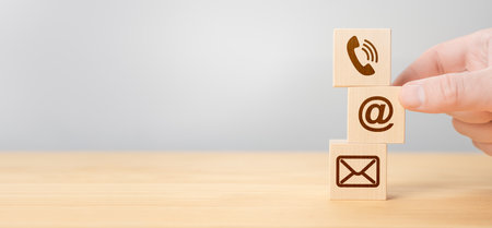 Hand Stacking wood Blocks with Icons mobile phone, email envelope telephone and e-mail address Against gray Background. Wooden cubes with symbol telephone, email, address. Contact usの写真素材