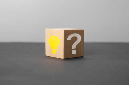 Wooden cube with bright light bulb and question mark on black table. Creative idea, Innovation and Solution concepts. Wooden cube with light bulb icon and question mark symbol. copy spaceの写真素材