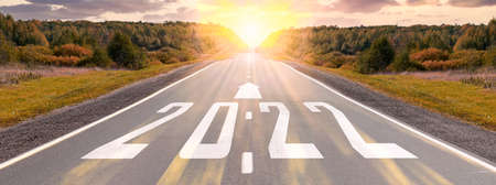 Empty asphalt road and New year 2022 concept. Driving on an empty road to Goals 2022 with sunset. 2022 written on highway road with arrow in empty asphalt road. Concept for vision 2021-2022.の写真素材