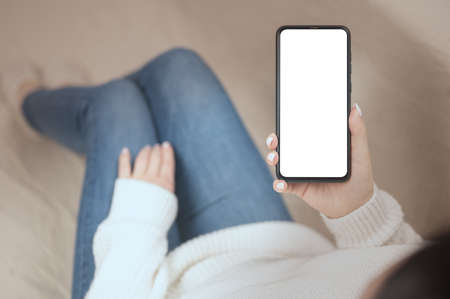 Mockup of cell phone held by woman in the living room. female reading text message on cell telephone...