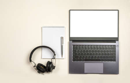 top view on laptop blank screen blank notepad and headphones on white table background with text space and copy space. Mockup image of modern white home office desk with laptop computerの写真素材