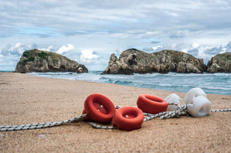 Beautiful sandy ocean beach with large rocks on shore and in water. floats from fishing nets. Ocean water splash on rock beach with Rugged cliffs. Peacock Beach Turkeyの写真素材