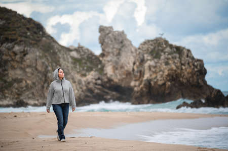 happy middle aged woman walking on beach