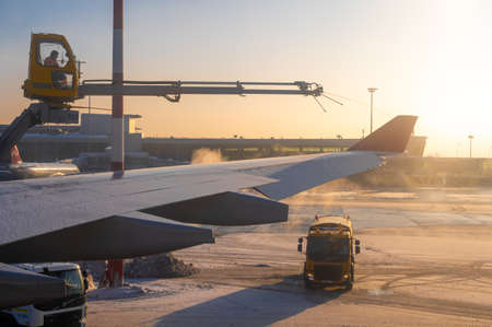 Moscow, Russia - January 12, 2022: Sheremetyevo International Airport. De-icing an aircraft wing. Process of spraying anti-icing white fluid the rear part of the wing of a plane at the airport at sunrise in winterのeditorial素材