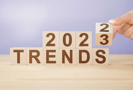 Businesswoman turns wooden cube and changes words 2022 to 20223 on very peri color background. Flipping of wooden cube block for change 2022 to 2023 yearの写真素材