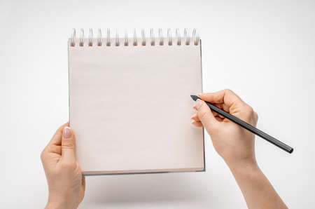 female hands writing in mockup notepad isolated on white. Woman writing in notepad. Mockup notepad with woman hands on white table backgroundの写真素材