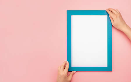 Woman hold blank diploma frame on pink wall background. Hanging photo frame mockup on pink wall. picture frame mockup. holding frame. Female hands hold mockup with white paper. copy spaceの写真素材