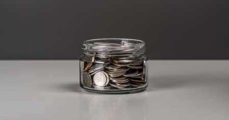 Coins in glass jar. currency money on dark gray background for business and finance concept. copyspace. Jar full of coins. Business, finance, saving money or investment conceptの写真素材