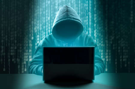 hack attack. Dangerous Hooded Hacker Breaks into Government Data Servers. Faceless hooded anonymous computer hacker on dark green background. Internet crime and electronic banking securityの写真素材