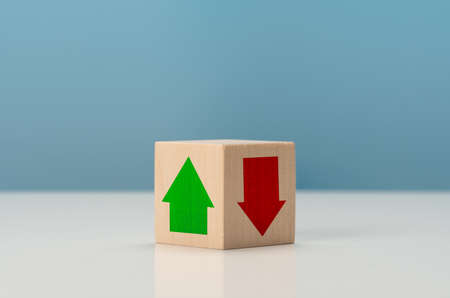 Rising and falling trends. green up arrow in bright side and red down arrow in dark side which print screen on wooden cube block for economic and business profit growth concept.の写真素材