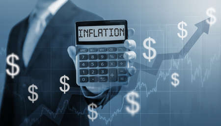 businessman holding calculator with word inflation on screen. decreasing purchasing power. inflation...