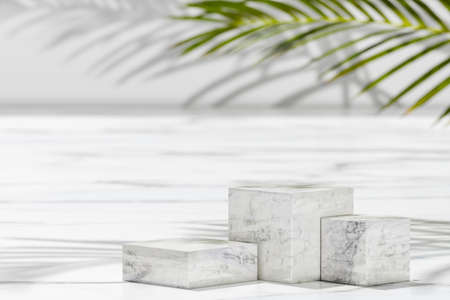 Podium for product presentation on natural background with three cubic marble pedestals under palm leaf and shadows. beauty cosmetic product display backgroundの写真素材