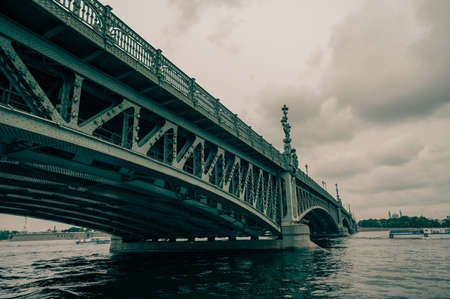 Bridge. A low metal bridge across the river in cloudy weather in gloomy dark colors. St. Petersburg. bridgeの写真素材