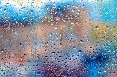 Drops Of Rain On Blue Glass Background. Street Bokeh Lights Out Of Focus. Autumn Abstract Backdrop. blurred outlines of buildingsの写真素材