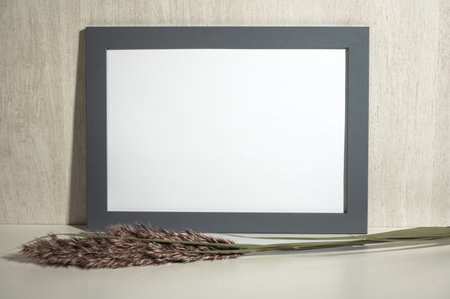 Horizontal gray frame mockup on vintage. Empty gray wooden frame stands on white table with dry...