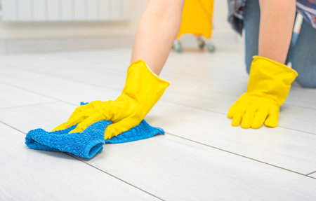 Deep cleaning service. Professional cleaner washing white floor in living room of apartment. female hands in gloves wipe white floor with text cleaning. Cleaning service conceptの写真素材