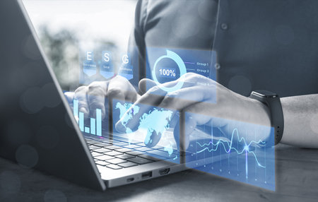 Businessman with laptop and virtual screen with graphs of financial and economic indicators. Digital transformation in global business. ESG- Environmental, Social, and Corporate Governanceの写真素材