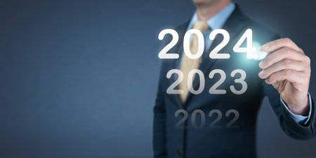 Hand businessman writing 2024 year on virtual screen. Business and Technology goals and achievement in 2024. Plans to increase business growth and an increase in indicators of positive growth 2024の写真素材