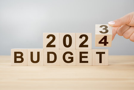 Business concept of planning 2024. Businessman flips wooden cube and changes words BUDGET 2023 to BUDGET 2024. New year business plan concept in 2024. Economy and business. Phrase 2024 BUDGETの写真素材