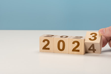 happy new year concept, Flipping of wooden cube block change from 2023 to 2024. Wooden cube with flip over block 2023 to 2024 word. Business management, Inspiration to success ideas and goals.の写真素材