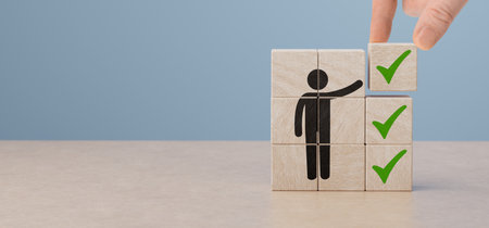 Wooden blocks checklist and green check mark icon with hand on table background. Business task sign appointment schedule concept. Businessman placing correct evaluation satisfaction checkbox symbolの写真素材