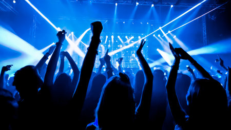 crowd dancing with neon blue lasers. People dancing at party with hands up. concert crowd in front of lit stage inside concert venue, during music festival. blue laser show in clubの素材