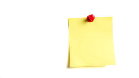 Yellow sticky note pinned on wall, blank space for text, office reminder, adhesive paper note, isolated on white, message board conceptの写真素材