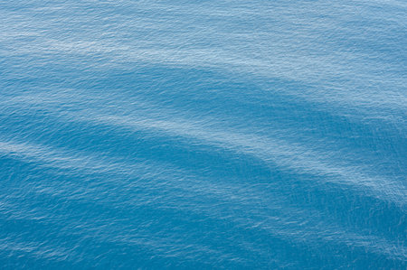 tranquil ocean water background with soft waves and subtle ripples. Blue sea surface reflects light. backgrounds, wallpapers, and nature-related projects. Captures essence of marine tranquilityの写真素材