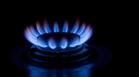 Gas burner glowing blue in dark, high fuel price, energy saving, household device, intense fire,...