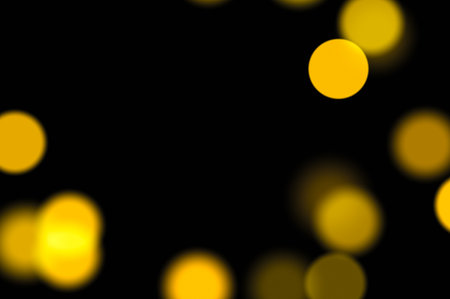 Abstract soft golden blurred light spots with dark contrast background suitable for party visuals warm ambiance vintage poster design or holiday projectsの写真素材