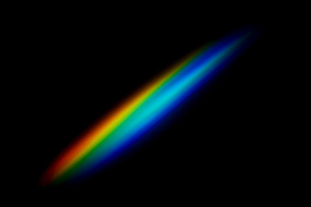 Vivid diagonal rainbow overlay with glowing spectrum colors isolated on dark background, perfect for creative graphic effects, backgrounds, science or cosmic space projectsの写真素材
