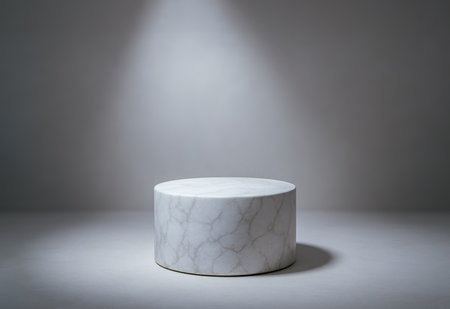 Simple white marble cylindrical podium under soft spotlight in minimal space, blank platform for mockup, cosmetics, branding, product presentation, or advertisingの写真素材