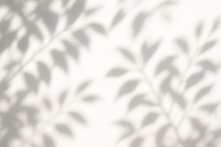 Soft leaf patterns cast by afternoon sun on pale neutral background offering serene minimalist atmosphere ideal for social media templates blog headers and product displaysの写真素材