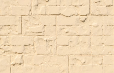 Closeup sand colored masonry facade showing uneven bricks and solid grout lines, an ideal empty backdrop for home renovation conceptsの写真素材