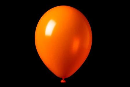 Inflated orange balloon, festive party decoration, shiny glossy finish, event celebration, birthday, isolated on black, happiness cheerful atmosphere, minimalの写真素材